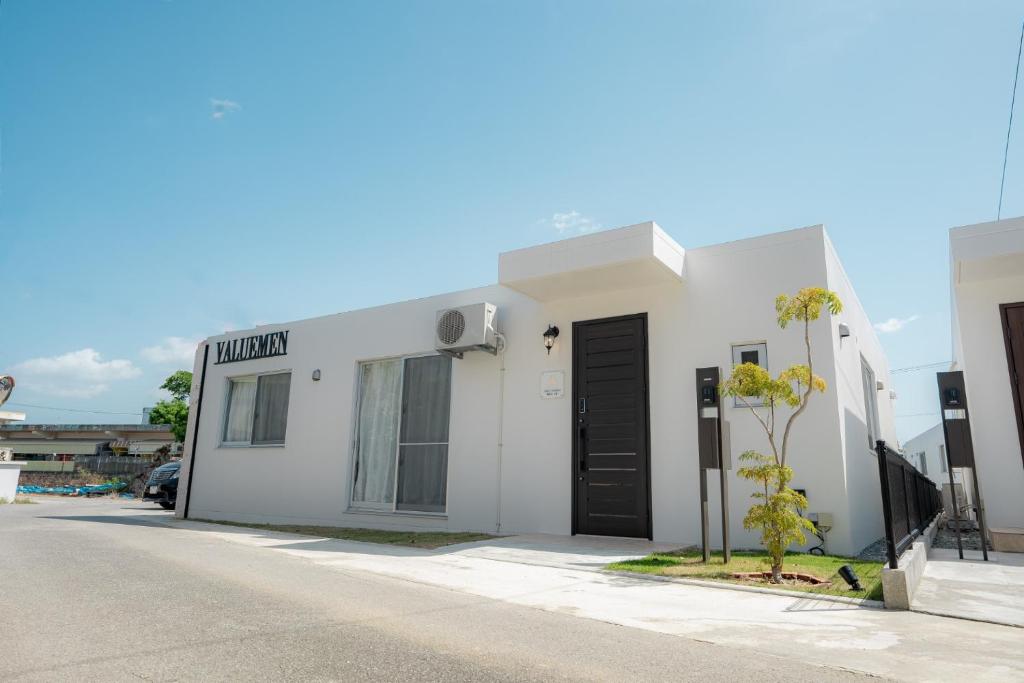 a white building with a black door on a street at Miyakojima - House - Vacation STAY 20446 in Hirara
