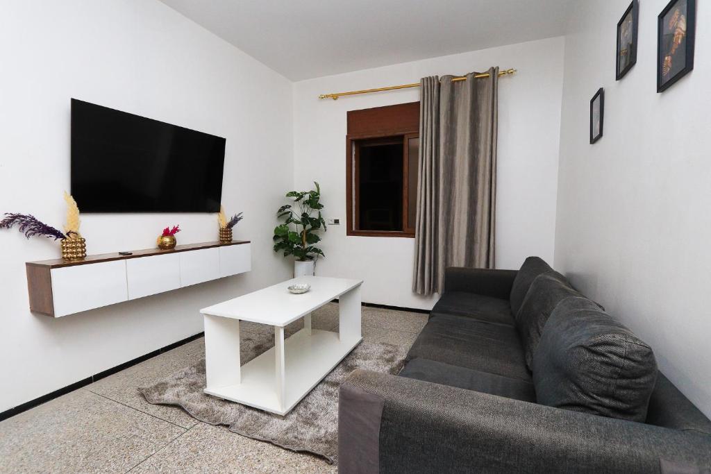 Una sala de estar con un sofá y un televisor en una pared. en New appartement in Salé, 10 min from Rabat, en Oulad Akkou