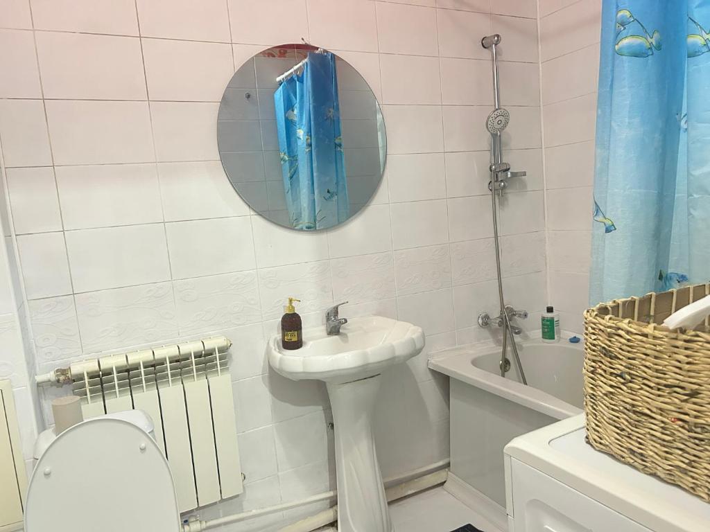 une salle de bain avec un lavabo, des toilettes et un miroir dans l'établissement Ayala, à Aqtöbe