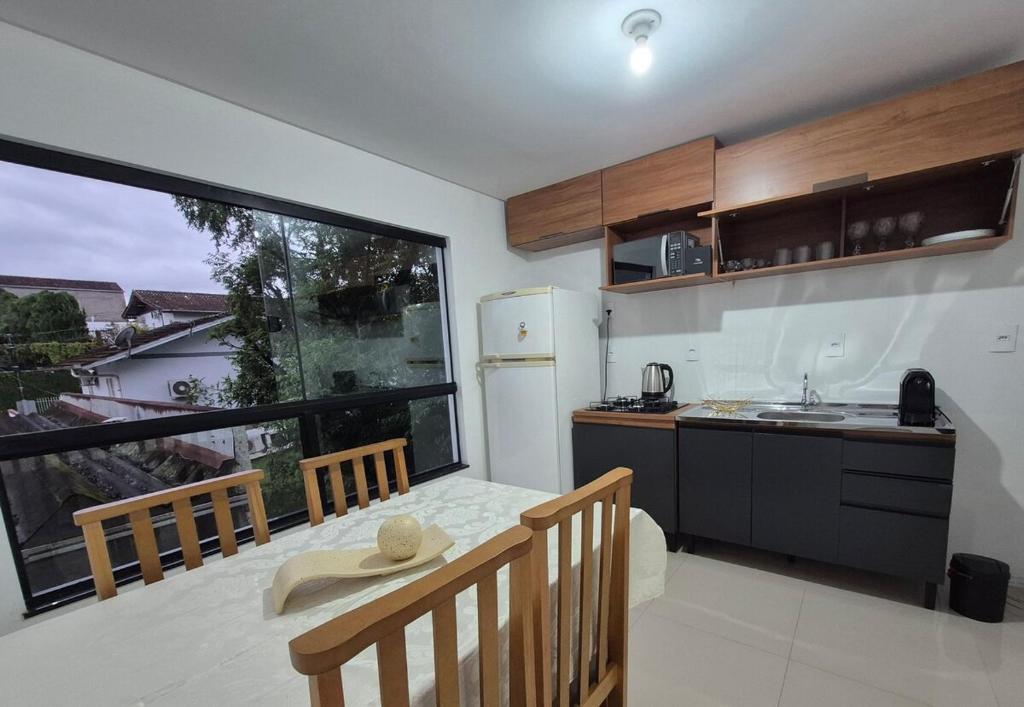 a kitchen with a table and a large window at Rent for Oktoberfest in Blumenau
