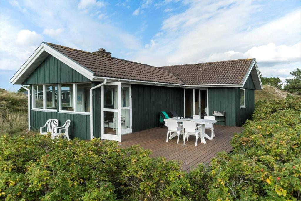 a green house with a table and chairs on a deck at FAN070-Fano-Nybyvej-58-B in Fanø