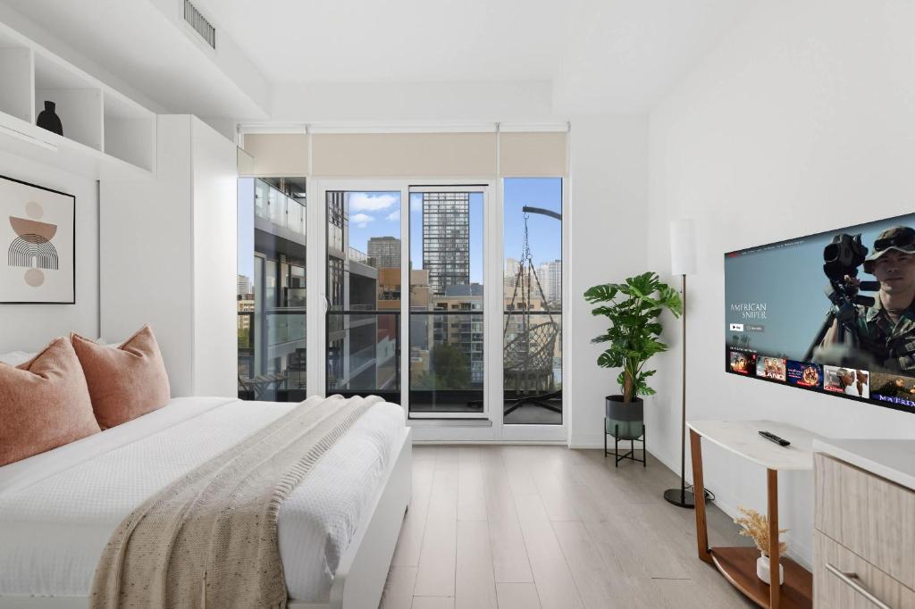 a white bedroom with a large bed and a flat screen tv at Modern Studio-Style Condo in Downtown Toronto in Toronto