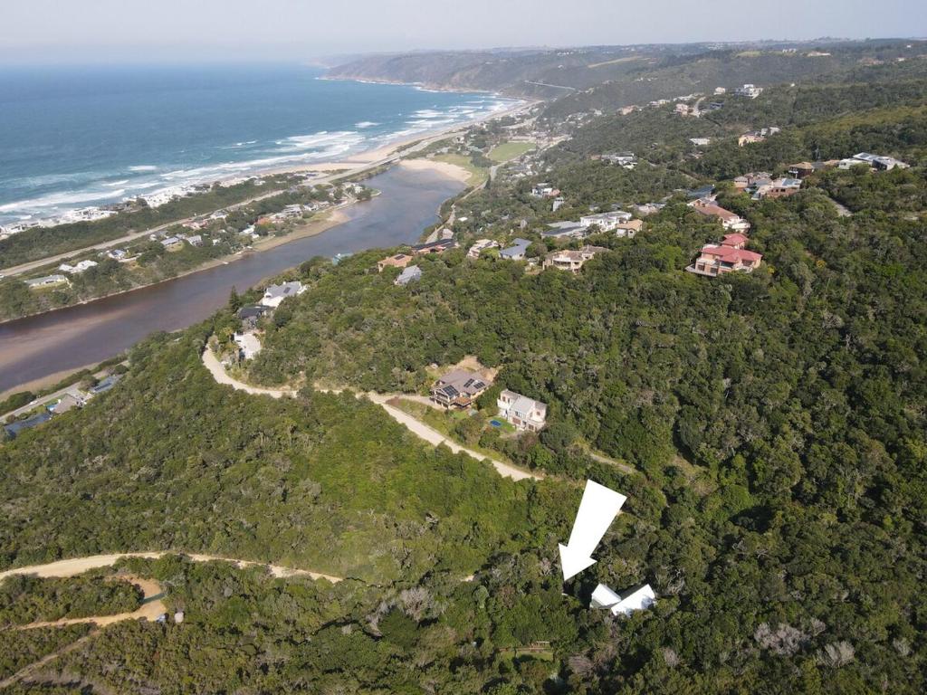 an aerial view of a house on a hill next to the ocean at Stone Cottage With Sea Views in Wilderness