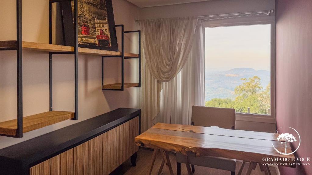 ein Esszimmer mit einem Tisch und einem Fenster in der Unterkunft Casa com piscina 3 suítes a 15 min Centro Gramado in Gramado