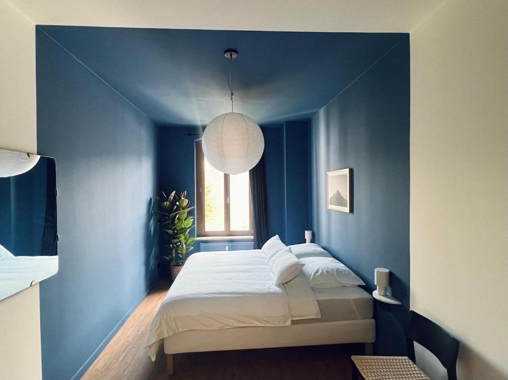 Un dormitorio azul con una cama y una ventana. en Atelier Noé NOIR - Kunstvoll Wohnen - Wunderbares Frühstück möglich - Ruhig und nah am Zentrum -, en Chemnitz