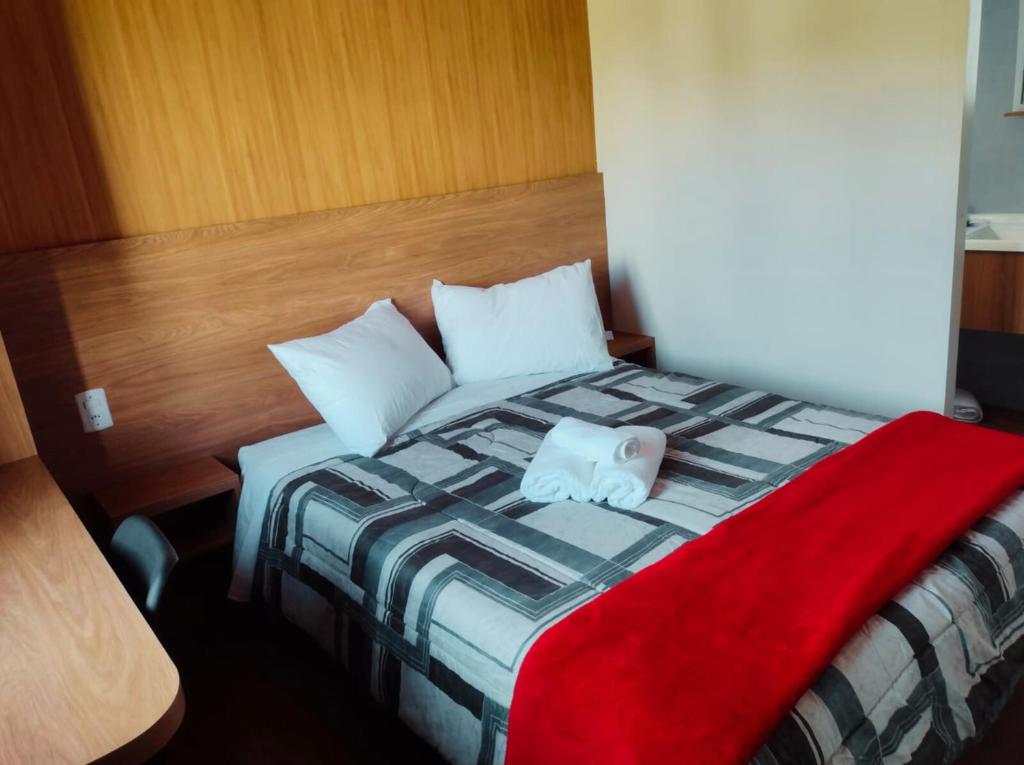 a bedroom with a bed with a red blanket on it at São Francisco de Paula - Quarto Confortável na Serra! in São Francisco de Paula