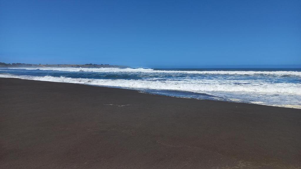 a beach with black sand and the ocean at Casa sector Vista Hermosa primera linea in Chacurra