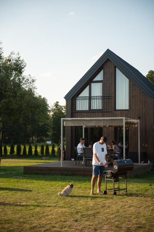 a man and a dog standing in front of a house at Uroczysko nad Pilicą Sauna & Balia in Pilica