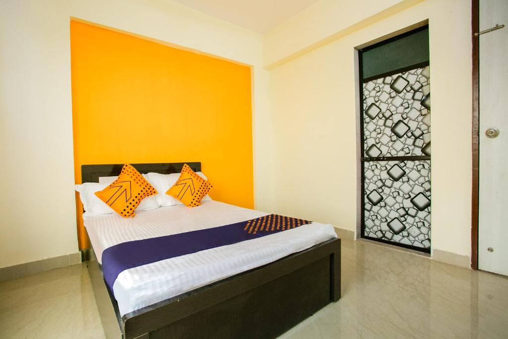 a bedroom with a bed with an orange and yellow wall at SPOT ON Pawan Villa in Gorhe