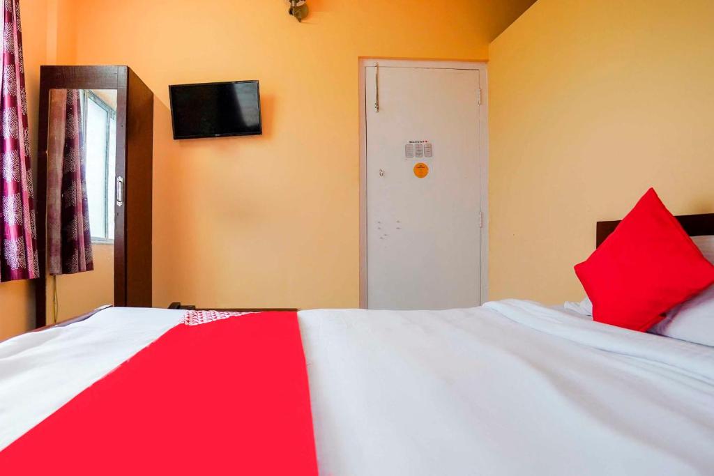 a bedroom with a bed with red pillows on it at Hotel O Urban Village Guest House in Kolkata