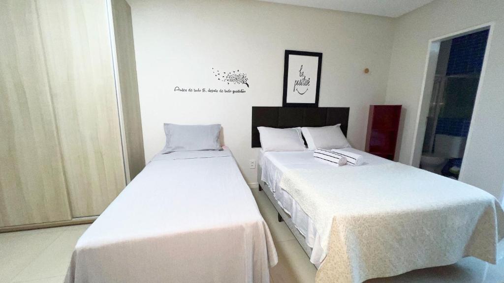 zwei Betten in einem Zimmer mit weißen Laken in der Unterkunft 700m da Praia de Atalaia com ar e piscina in Santa Maria