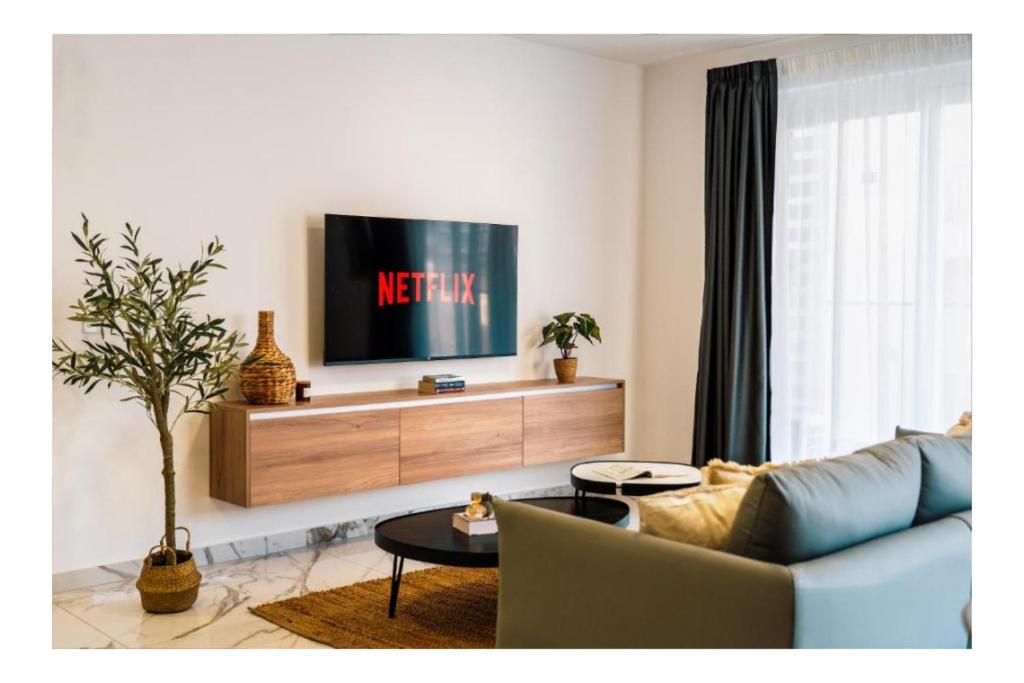Una sala de estar con un sofá y un televisor. en Corner Spacious 2BR Apartment - by HostMT, en St Paul's Bay