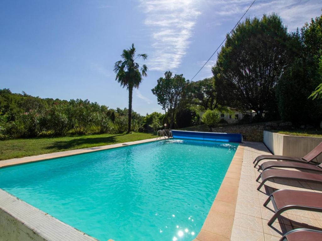 a swimming pool with chairs and a palm tree at Maison avec Piscine Privée et Wifi en Dordogne - FR-1-616-501 in Maurens