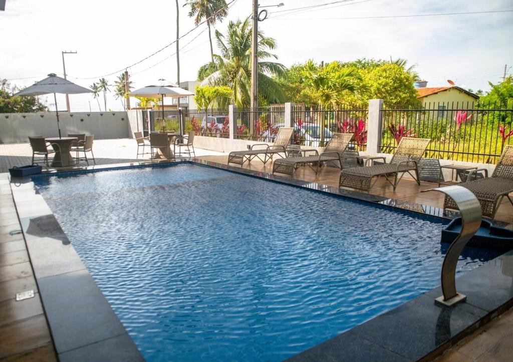 een zwembad met stoelen en een tafel bij Apto com Piscina e Churrasqueira Perto da Praia in São Bento