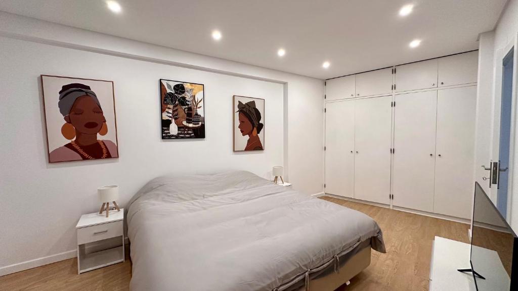 Un dormitorio con una cama y algunos cuadros en la pared. en Maxwell Apartments Quarteira, en Quarteira
