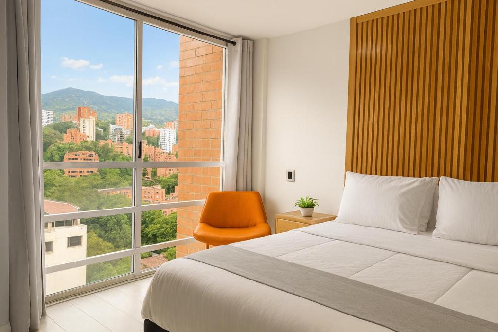 a bedroom with a bed and a large window at Edificio La Frontera - Vista El Poblado Free Parking & Wifi Recep 24 h in Medellín