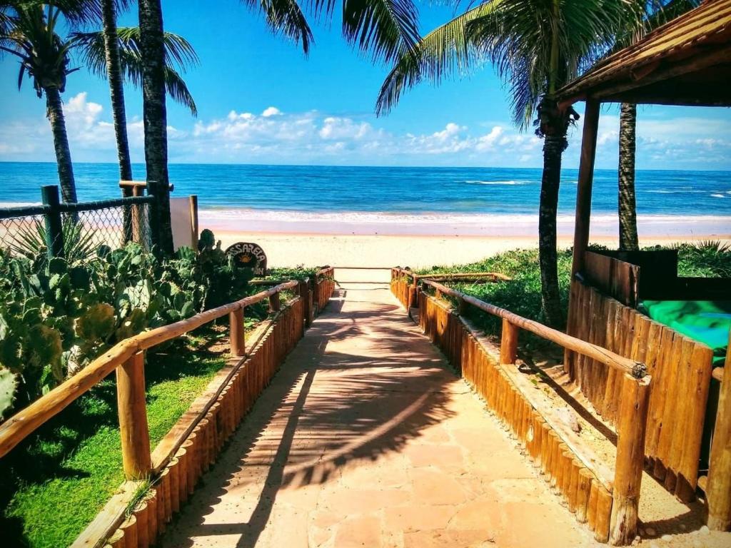 a pathway to the beach with palm trees and the ocean at Flat Pé na Areia em Guarajuba Summer House, Bahia in Monte Gordo