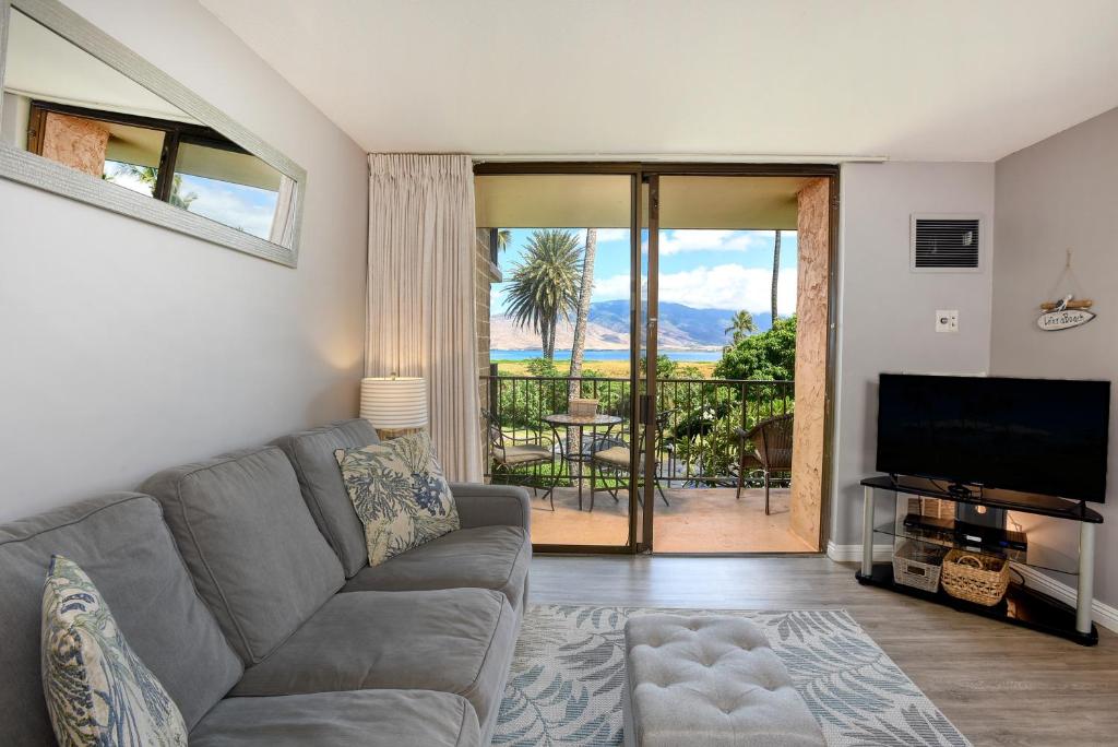a living room with a couch and a television and a balcony at Kauhale Makai 212 in Kihei