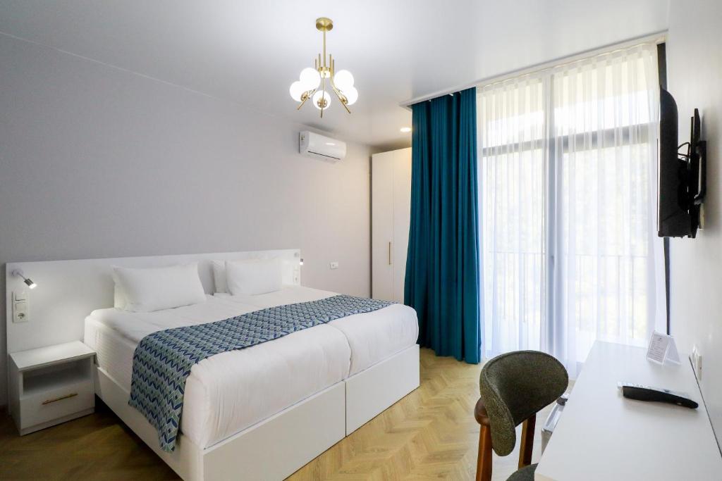a bedroom with a bed and a desk and a television at Emerald Borjomi Hotel in Borjomi