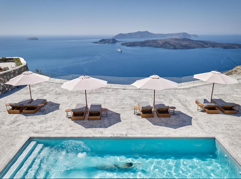 a swimming pool with chairs and umbrellas on a beach at Nafsika Estate in Megalokhori