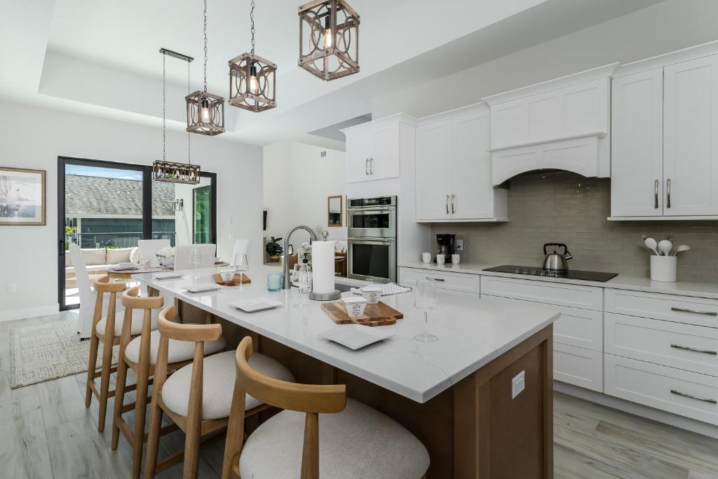 a kitchen with white cabinets and a large island with bar chairs at Aloha Nani Hilo in Isles of Capri