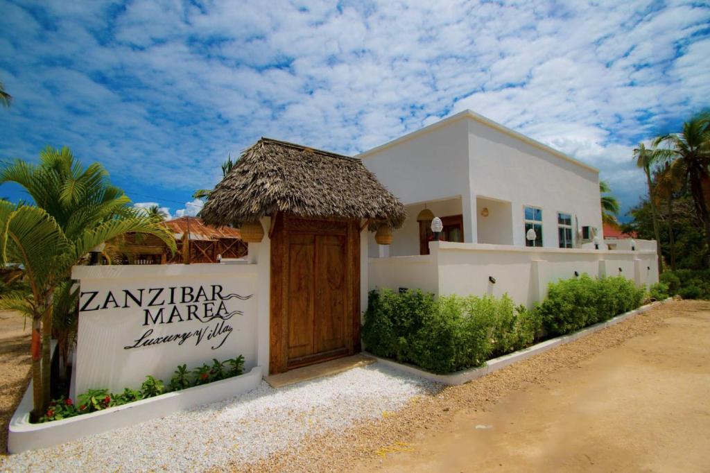 a white house with a wooden door in front at ZANZIBAR MAREA Luxury Villas in Kiwengwa