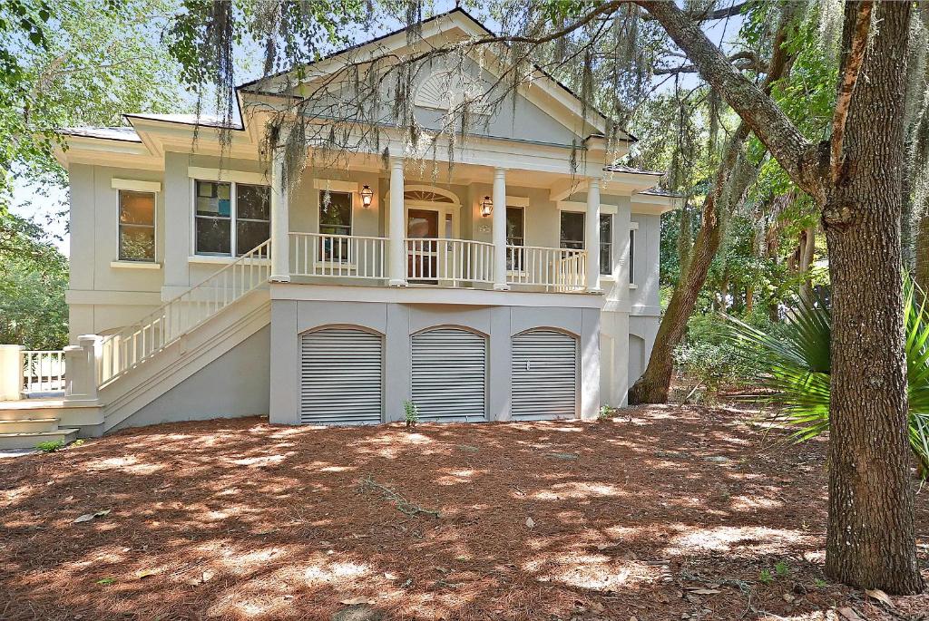a large white house with a porch and a tree at OG14: 14 Ocean Green in Kiawah Island