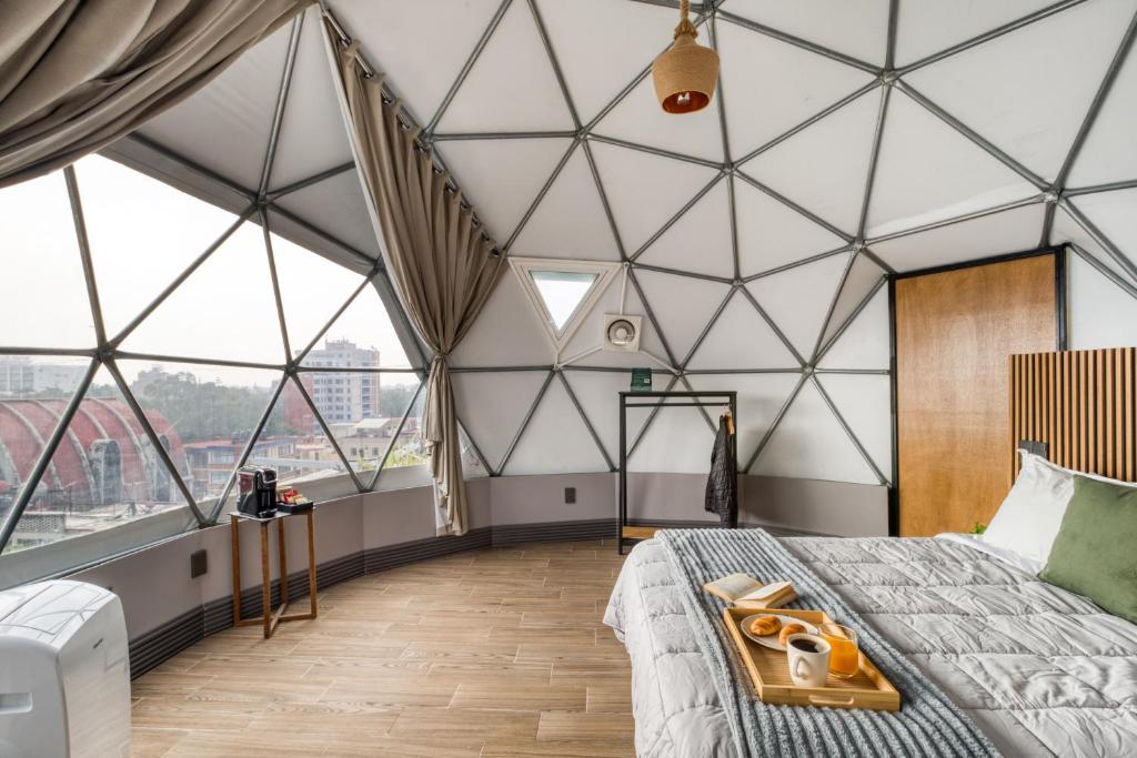 Habitación con cama y ventanas grandes. en Casa Umbral Glampings, en Ciudad de México