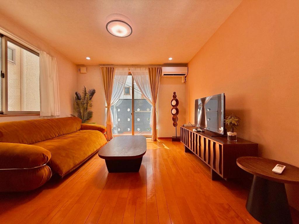 a living room with a couch and a tv at 4-5F Ikebukuro Business District hotel, 9 mins to ST Max 4P 池袋商务区 全新装修 交通中心 车站9分钟 最大4人 直达新宿 涉谷 表参道 品川 池袋 上野 代代木 银座 原宿 in Wada