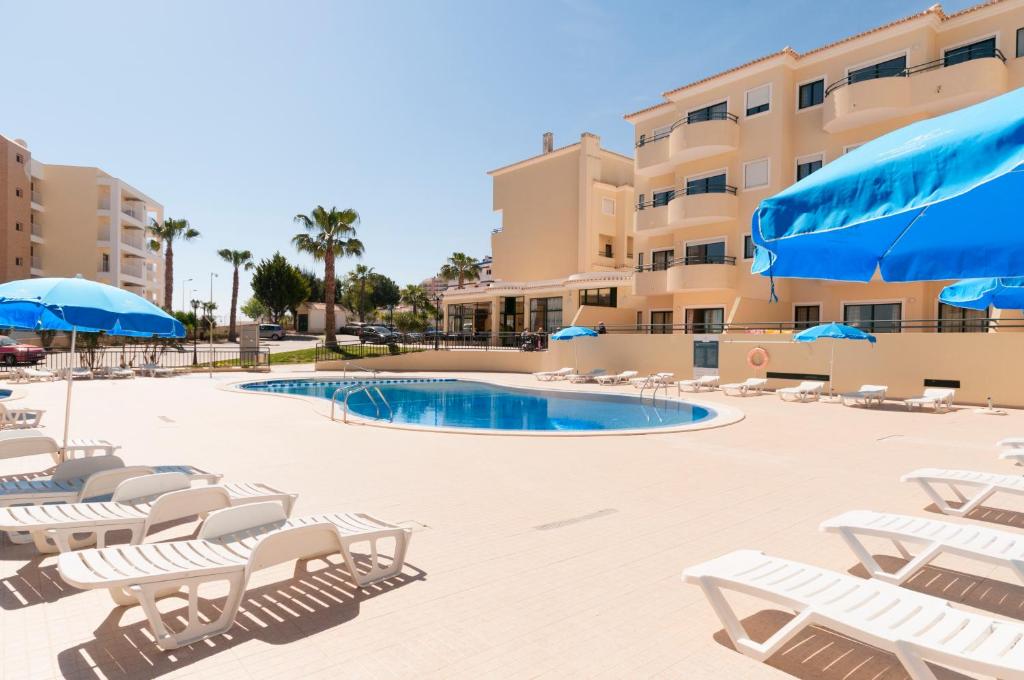 a swimming pool with lounge chairs and umbrellas at Plaza Real by Atlantichotels in Portimão