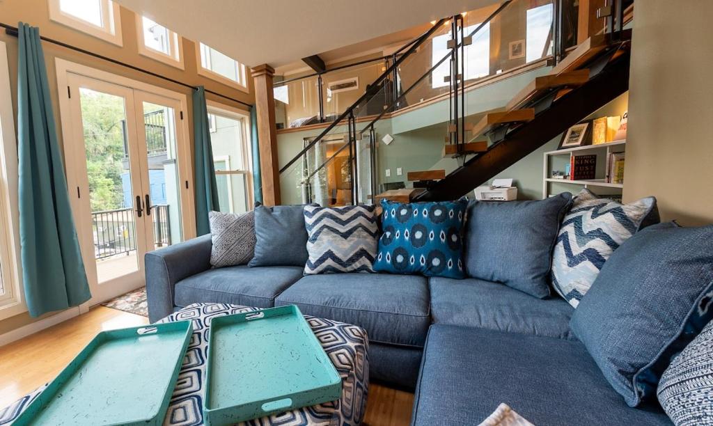 een woonkamer met een blauwe bank en een trap bij Luxury spacious home, free parking, private patios in Eureka Springs