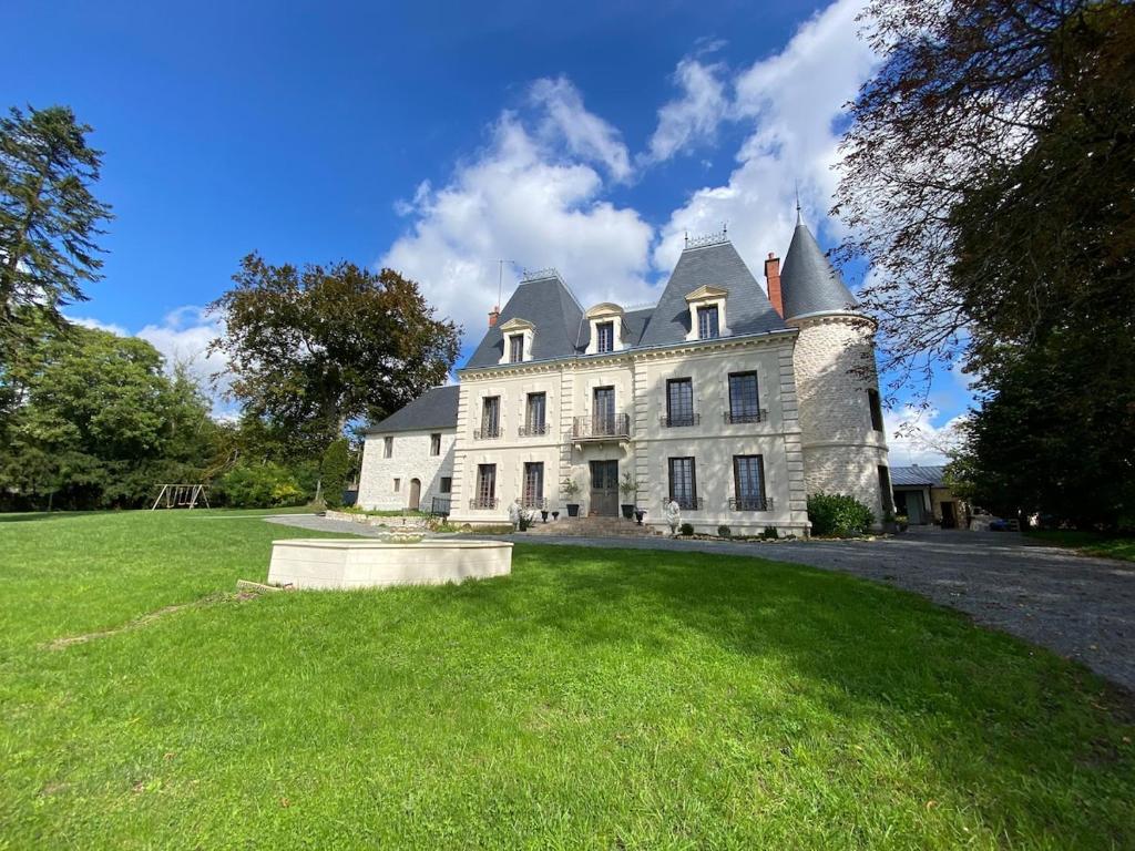 a large white house with a turret on a grass field at Studio Cosy dans les granges d un château accès spa in Varennes Vauzelles