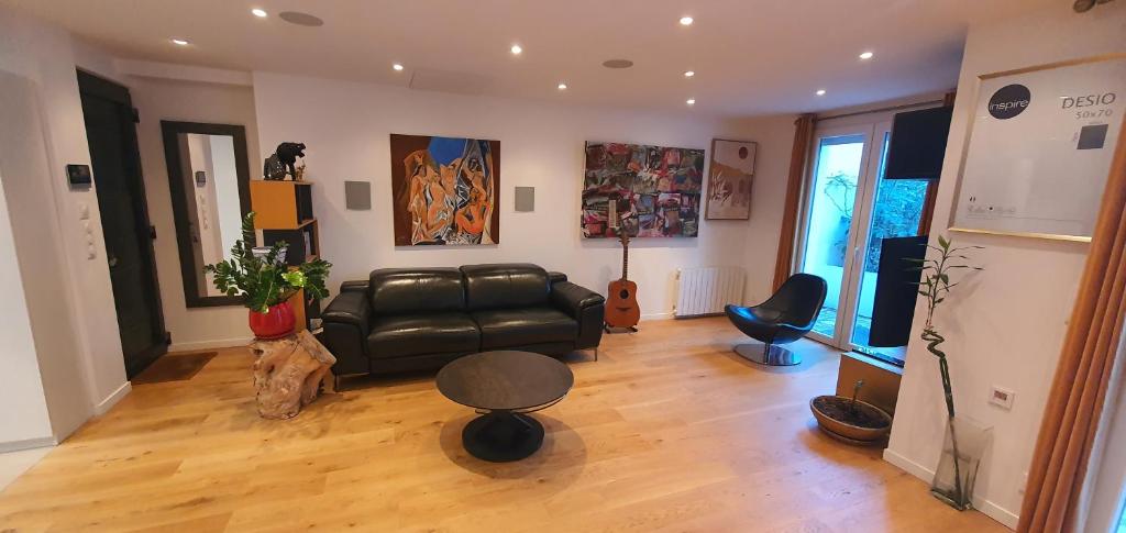 a living room with a black leather couch and a table at Superbe logement au style Londonien Avec Cinema Ideal pour des grandes familles et professionnels in Drancy