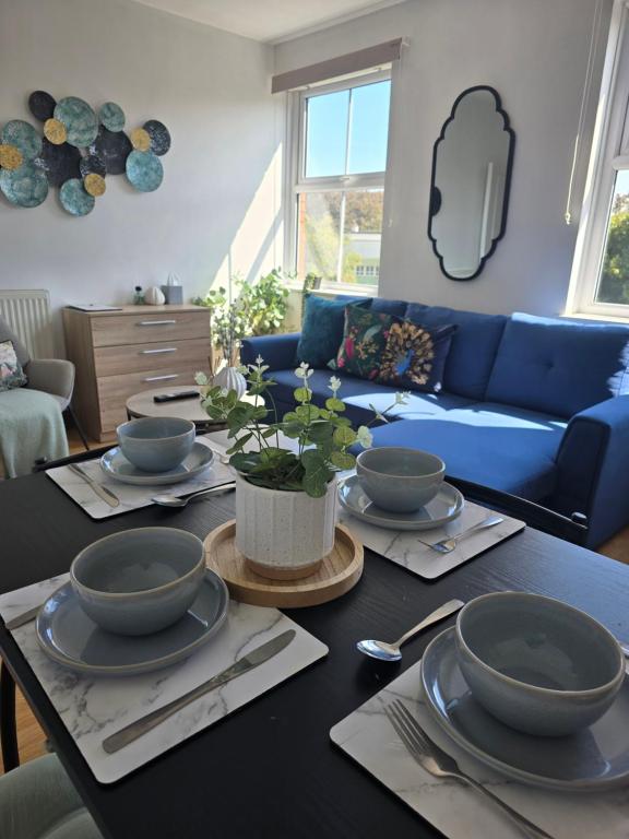 a table with bowls and plates and a blue couch at Southampton City Centre Apartment Free Private Parking in Southampton