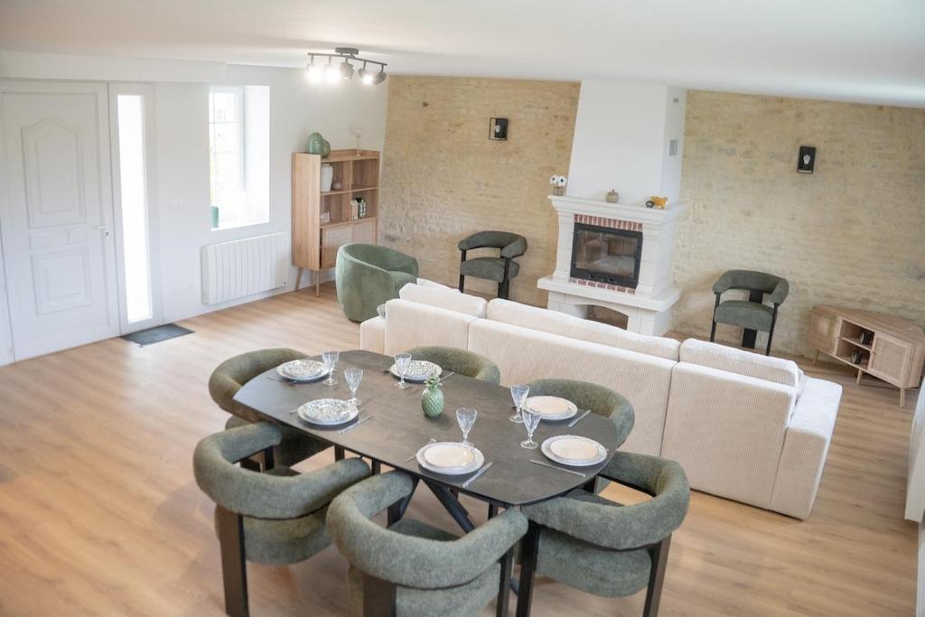 ein Wohnzimmer mit einer Couch und einem Tisch und Stühlen in der Unterkunft Le Perrées cottage Peace and Tranquility in Juaye-Mondaye