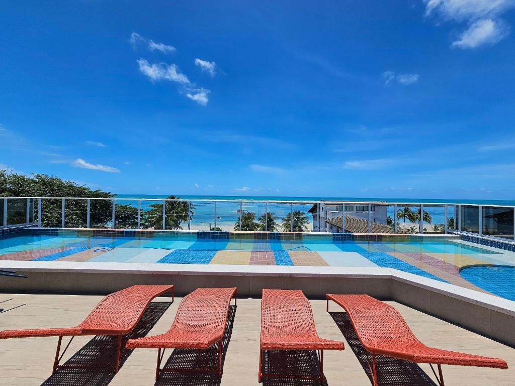 a balcony with chairs and a swimming pool at Mila Rooftop - Praia de Tamandaré in Tamandaré