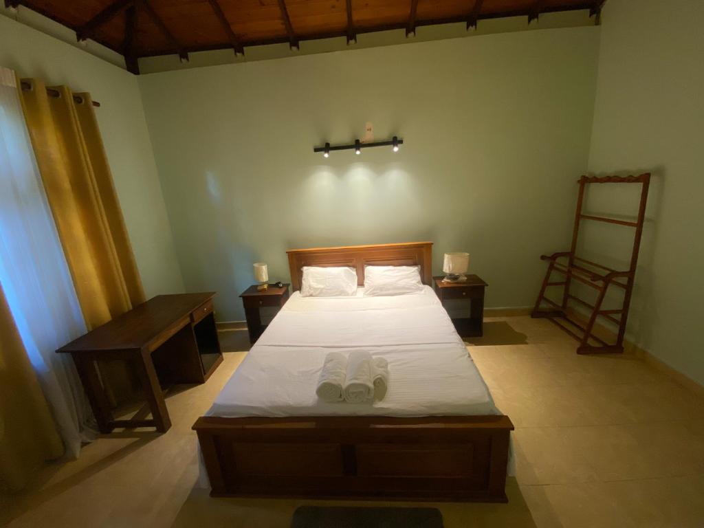 ein Schlafzimmer mit einem Bett mit einem Paar Schuhe darauf in der Unterkunft Elegance Cottage in Nikawatawana