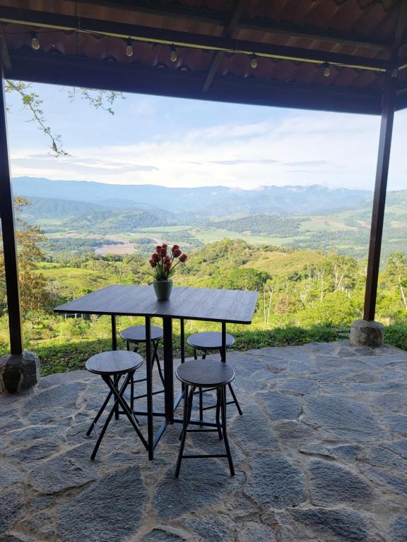 a table with two chairs and a vase with flowers on it at Cabaña Doña Flor in Turrialba