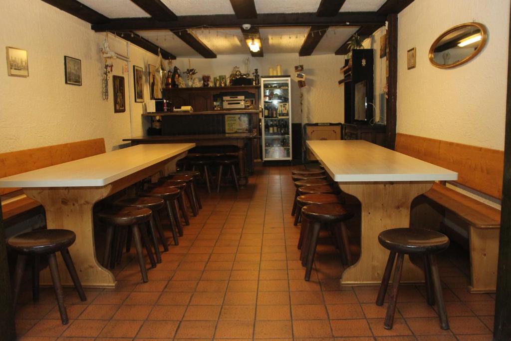 a bar with wooden tables and stools in a restaurant at La Cordée in Ovronnaz