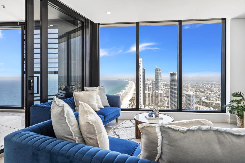 a living room with blue couches and large windows at Oceans Suites - Q Stay in Gold Coast