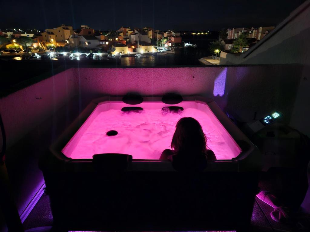 a woman sitting in a hot tub at night at Nautica bulles jacuzzi privatif vue lac marin in Le Barcarès