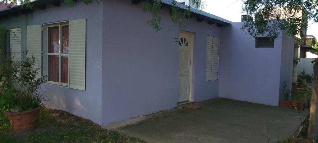 a white house with a door and a porch at La Gringa in Villa Elisa