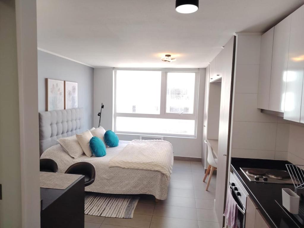 a small bedroom with a bed with blue pillows at Depto Estudio Full equipado con Estacionamiento in Concepción
