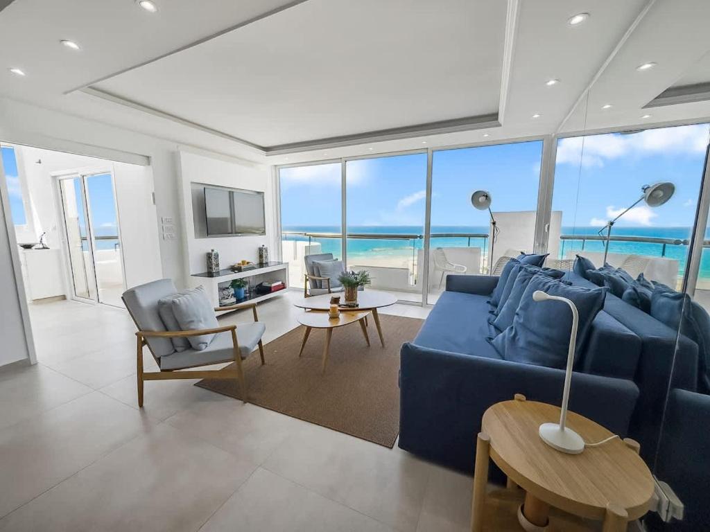 a living room with a blue couch and the ocean at Blue Horizon Penthouse in Herzliya B
