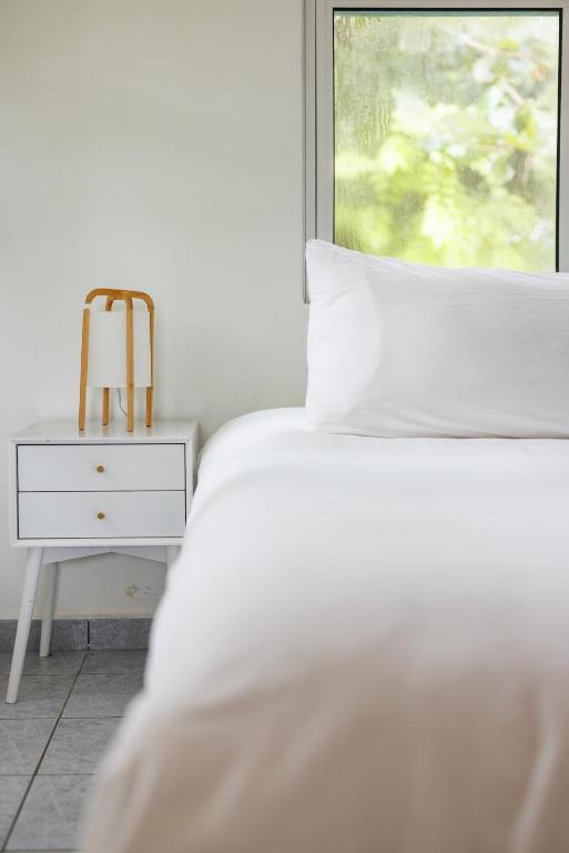 林康Serenity Rincon Guesthouse的一间卧室，有一张白色的床和一扇窗户