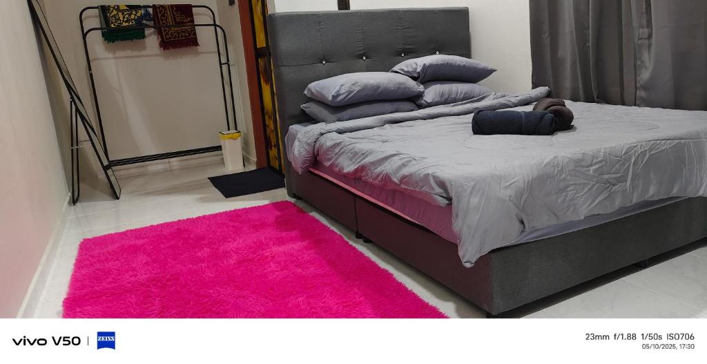 a bedroom with a bed with a pink rug at ZZD Gunong Roomstay in Bachok