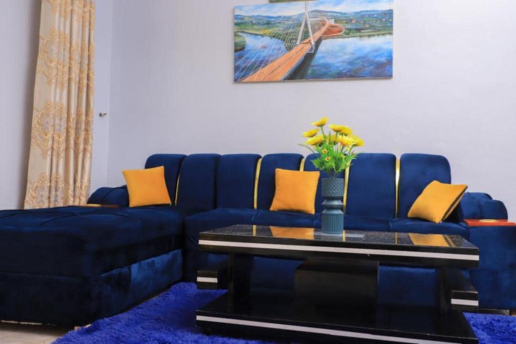a living room with a blue couch and a table at Pineapple Apartments in Jinja