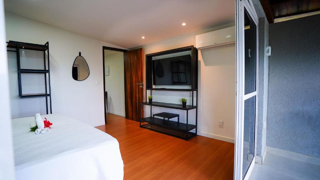 une chambre avec un lit blanc et une télévision dans l'établissement Flat Exclusivo com Piscina Privativa e Vista Incrível, à Fernando de Noronha