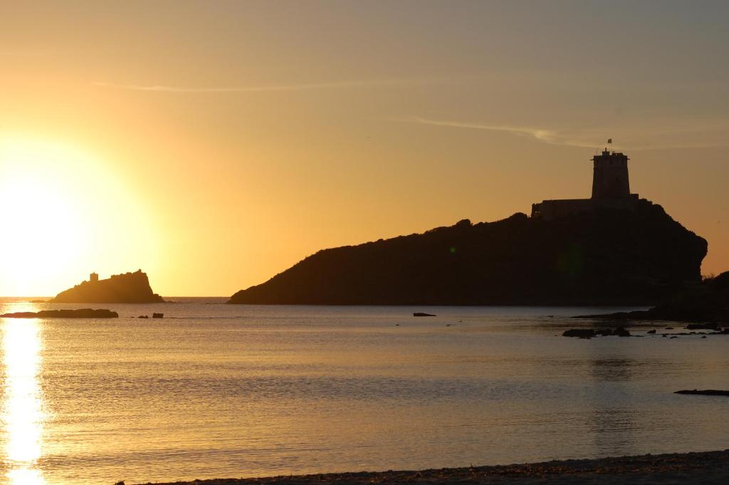 ein Leuchtturm auf einer Insel im Ozean bei Sonnenuntergang in der Unterkunft Casa Vacanze - Villa San Pietro in Villa San Pietro