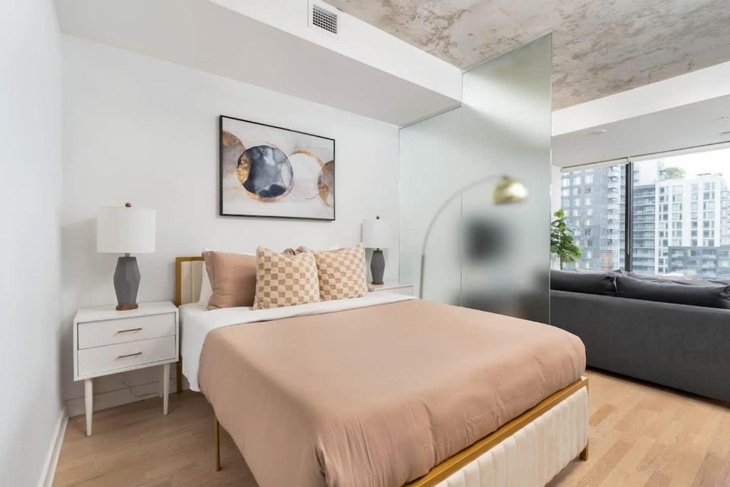 a white bedroom with a large bed and a couch at Urban Oasis Condo with Cafe & Bar at Your Doorstep in Toronto